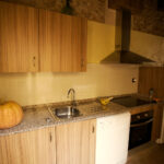 "Cuina amb taulell de fusta, forn, microones i nevera."