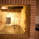 "Antic pou amb cub de metall, cobert amb vidre i envoltat de maons a la cuina."